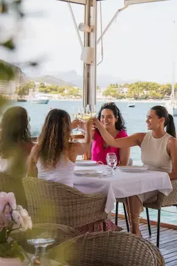 Grupo de amigas brindando durante una comida con vistas al mar