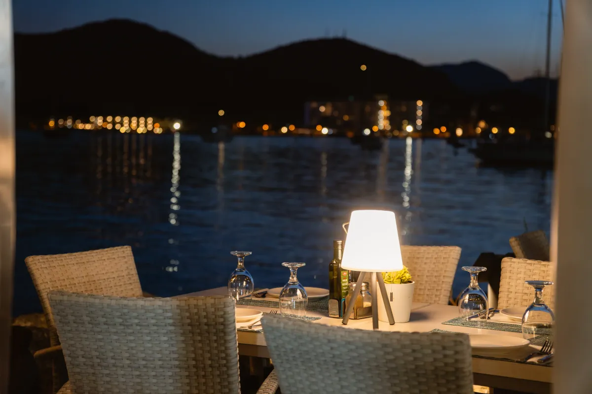 Mesa de la terraza de noche con las luces del puerto al fondo